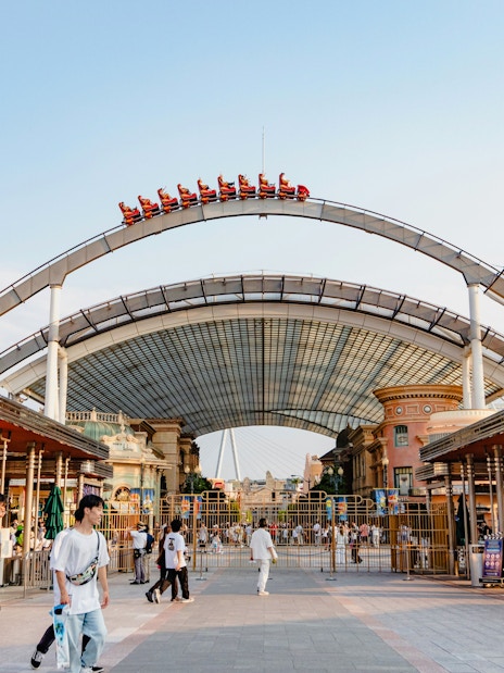 Entrance to Universal Studios Japan with roller coaster track overhead.