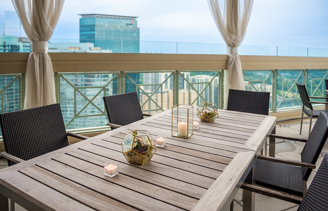 Wooden tables and chairs on a restaurant balcony overlooking Atlanta skyline.