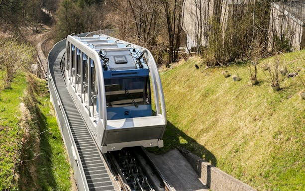 Nordkettenbahn funicular ascending through forested area in Innsbruck.