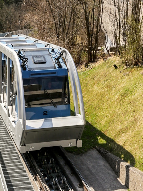 Funicular railway ascending a hillside in a wooded area.