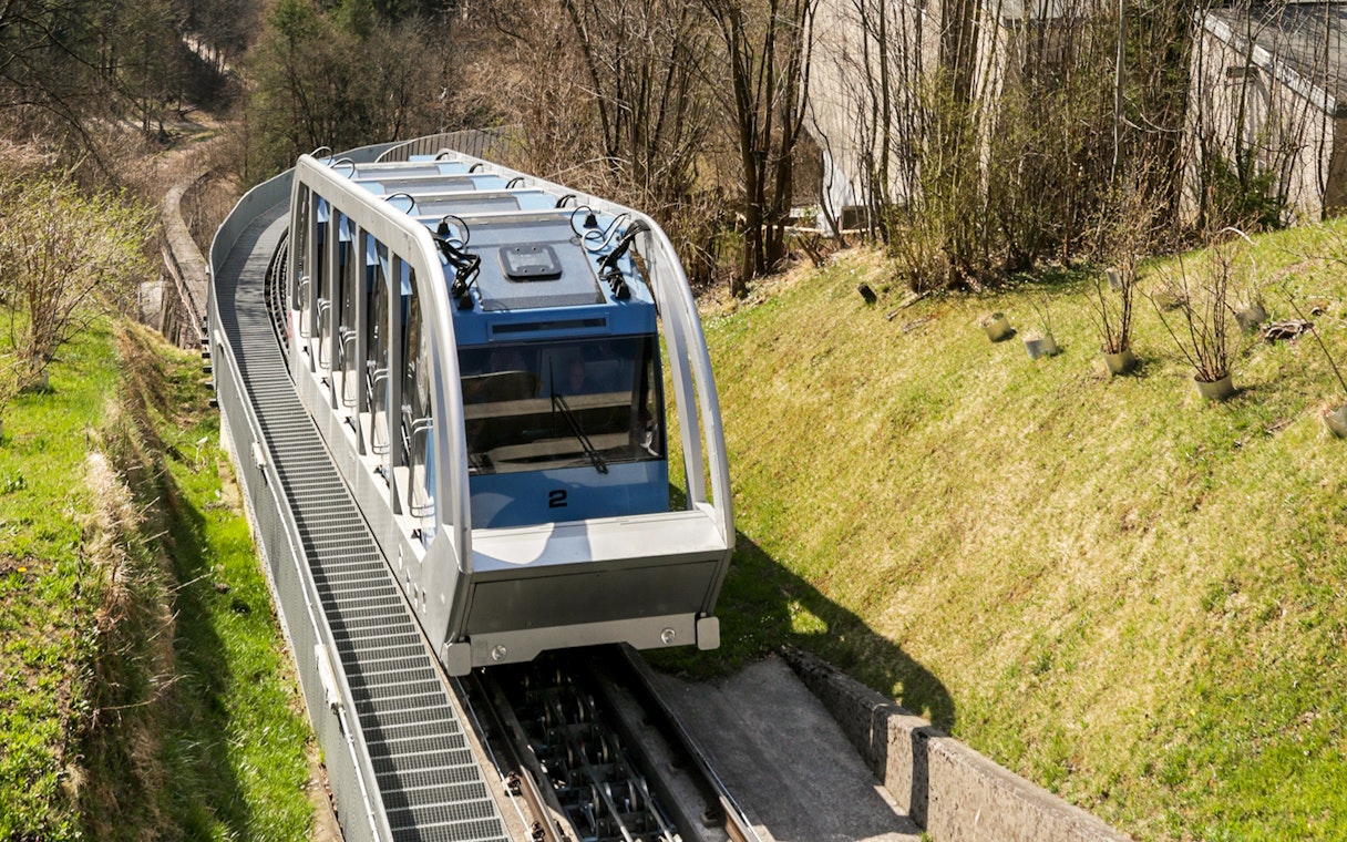 Funicular railway ascending a hillside in a wooded area.
