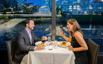 Couple dining on a Chicago river cruise with city skyline view.
