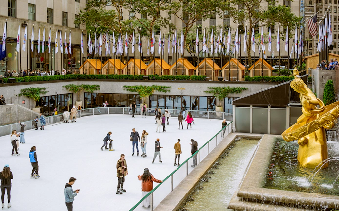 Tourists ice skating at The Rink in Rockefeller Center, New York City.