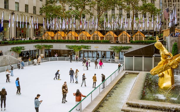 Tourists ice skating at The Rink in Rockefeller Center, New York City.