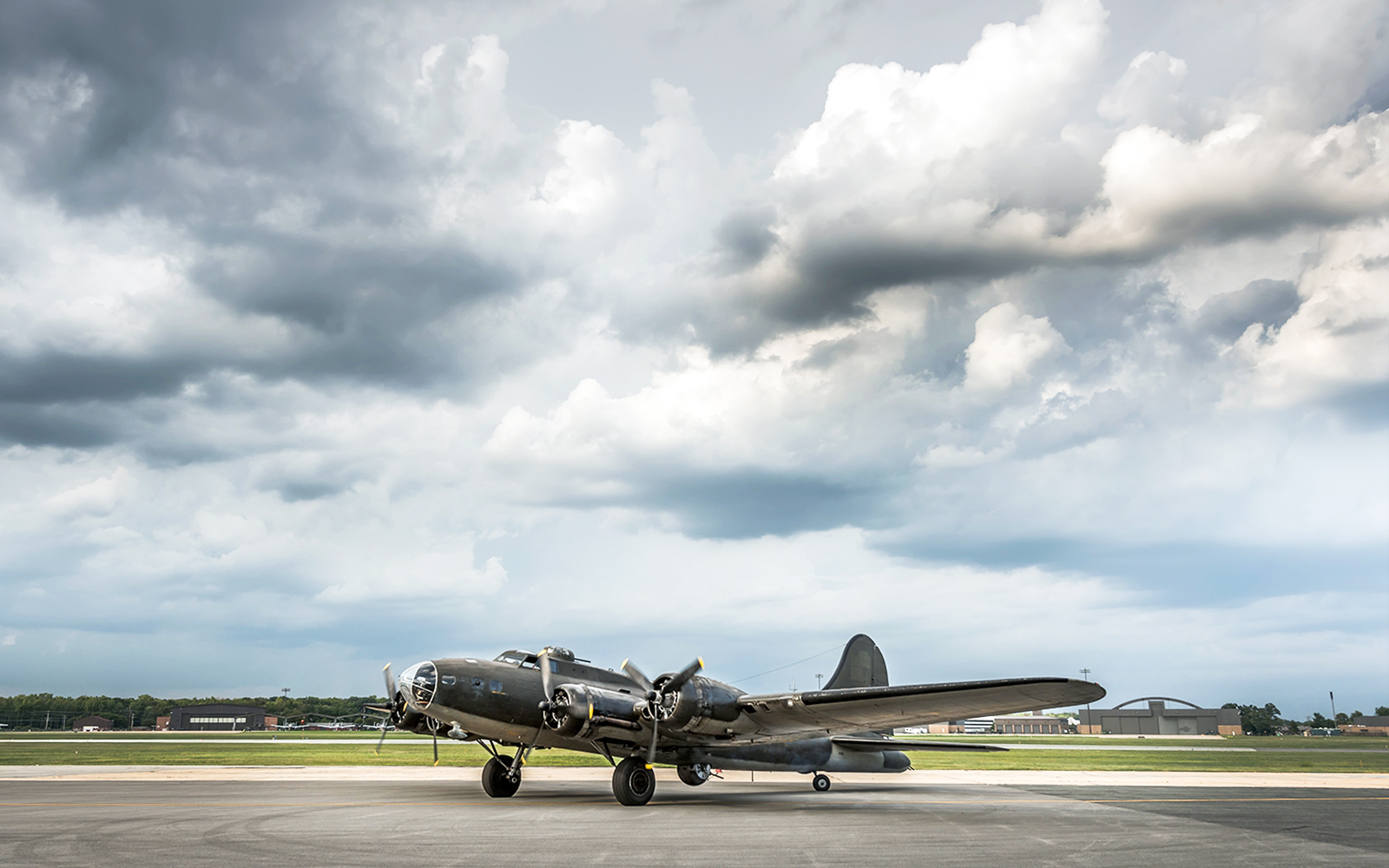 American World War Two bomber aircraft on runway under cloudy sky.