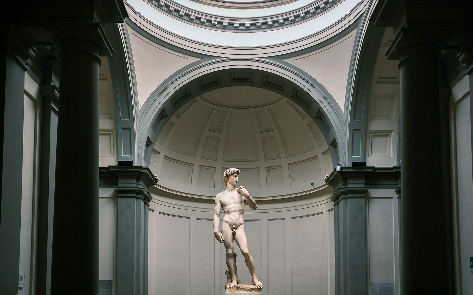 David of Michelangelo statue at Accademia Gallery, Florence with tourists viewing.