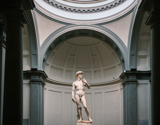 David of Michelangelo statue at Accademia Gallery, Florence with tourists viewing.