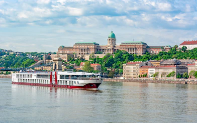 Cruise ship on the Danube River with Buda Castle in Budapest.