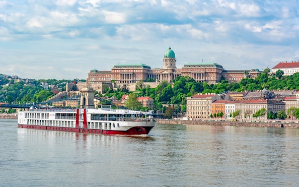 Cruise ship on the Danube River with Buda Castle in Budapest.