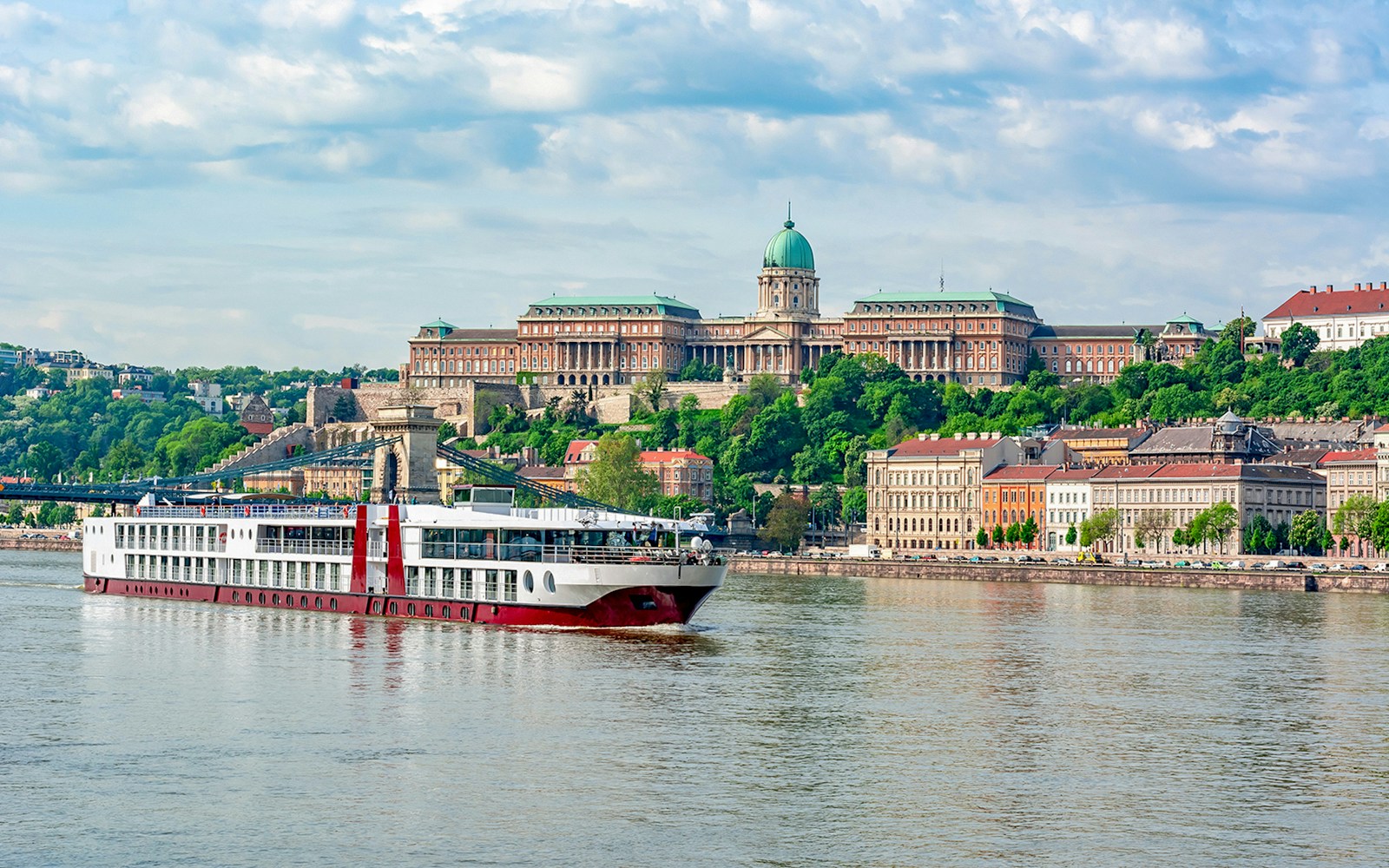 Cruise ship on the Danube River with Buda Castle in Budapest.
