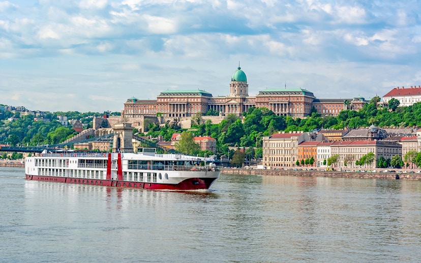 Cruise ship on the Danube River with Buda Castle in Budapest.