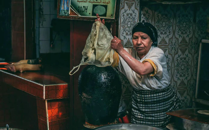 Artisan preparing traditional goods in Fes souk during city tour.