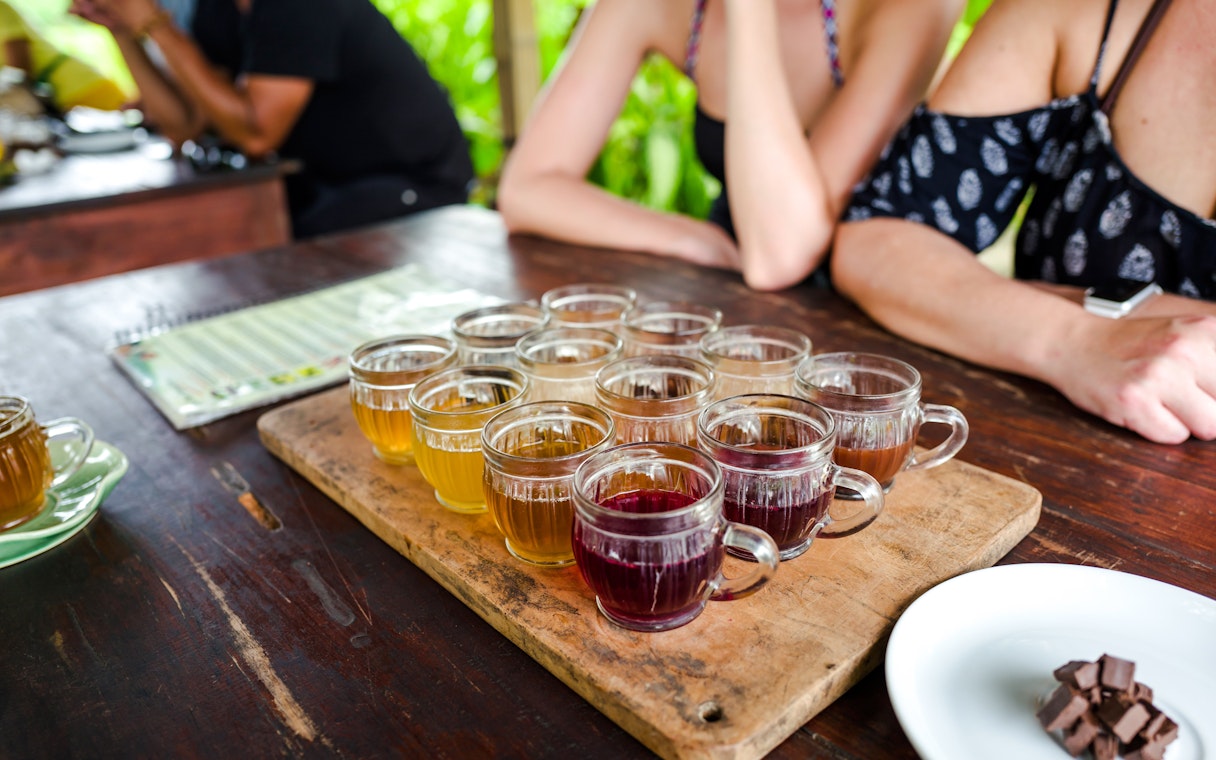 Coffee tasting session with various brews on a wooden tray in Bali.