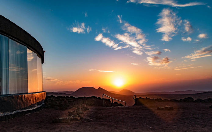 Sunset view at Timanfaya National Park with volcanic landscape and restaurant window.