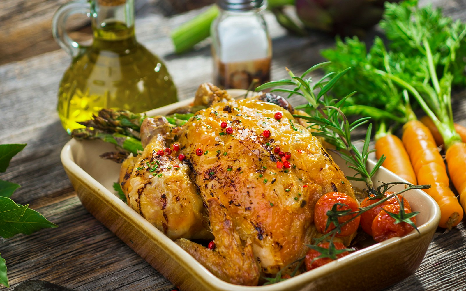 French roast chicken with herbs and vegetables in a dish.