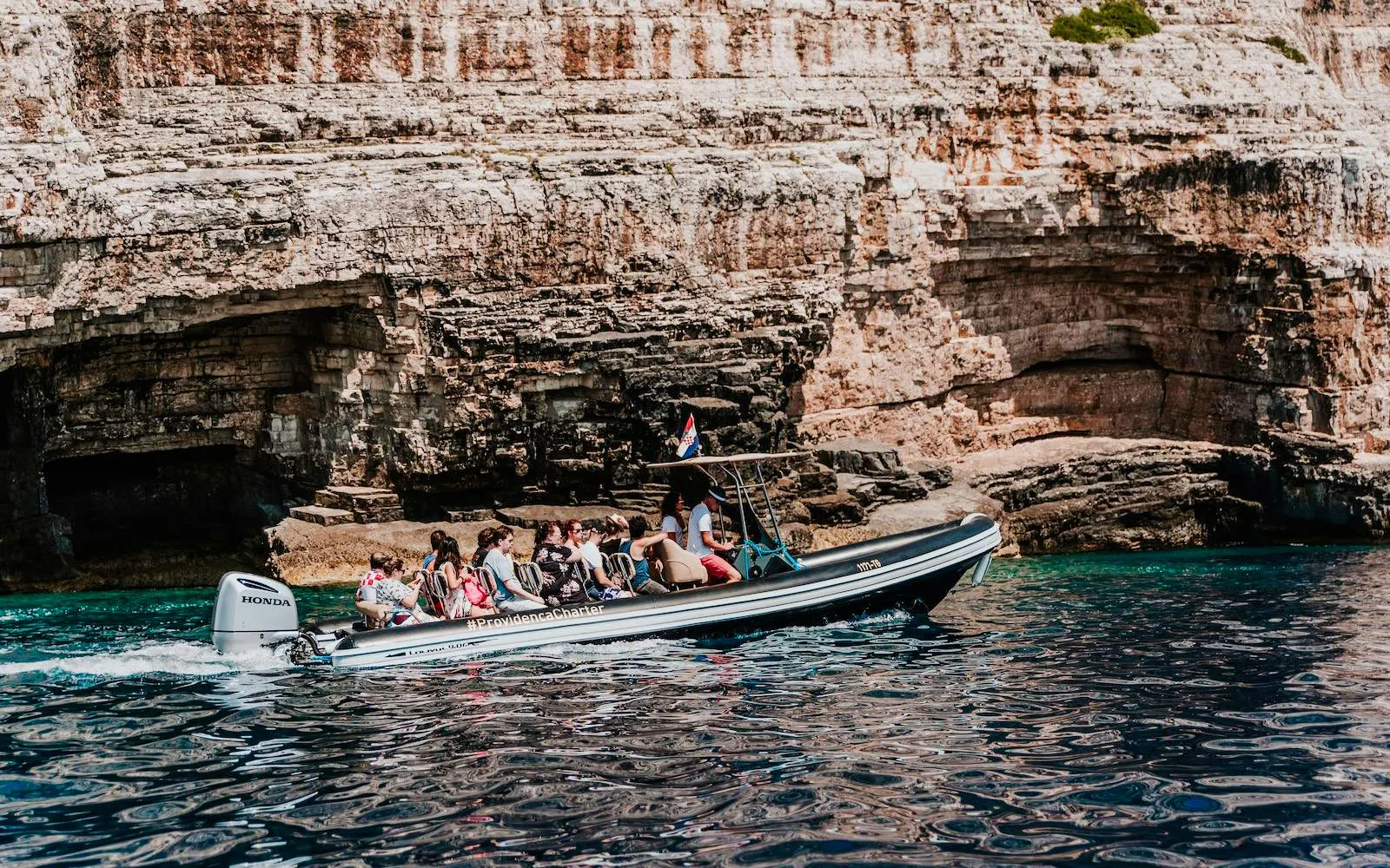 Speedboat with tourists near rocky cliffs on Blue Cave tour from Split.
