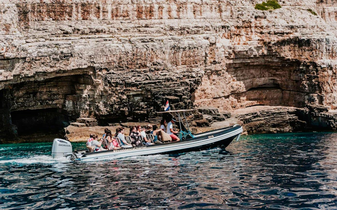 Speedboat with tourists near rocky cliffs on Blue Cave tour from Split.