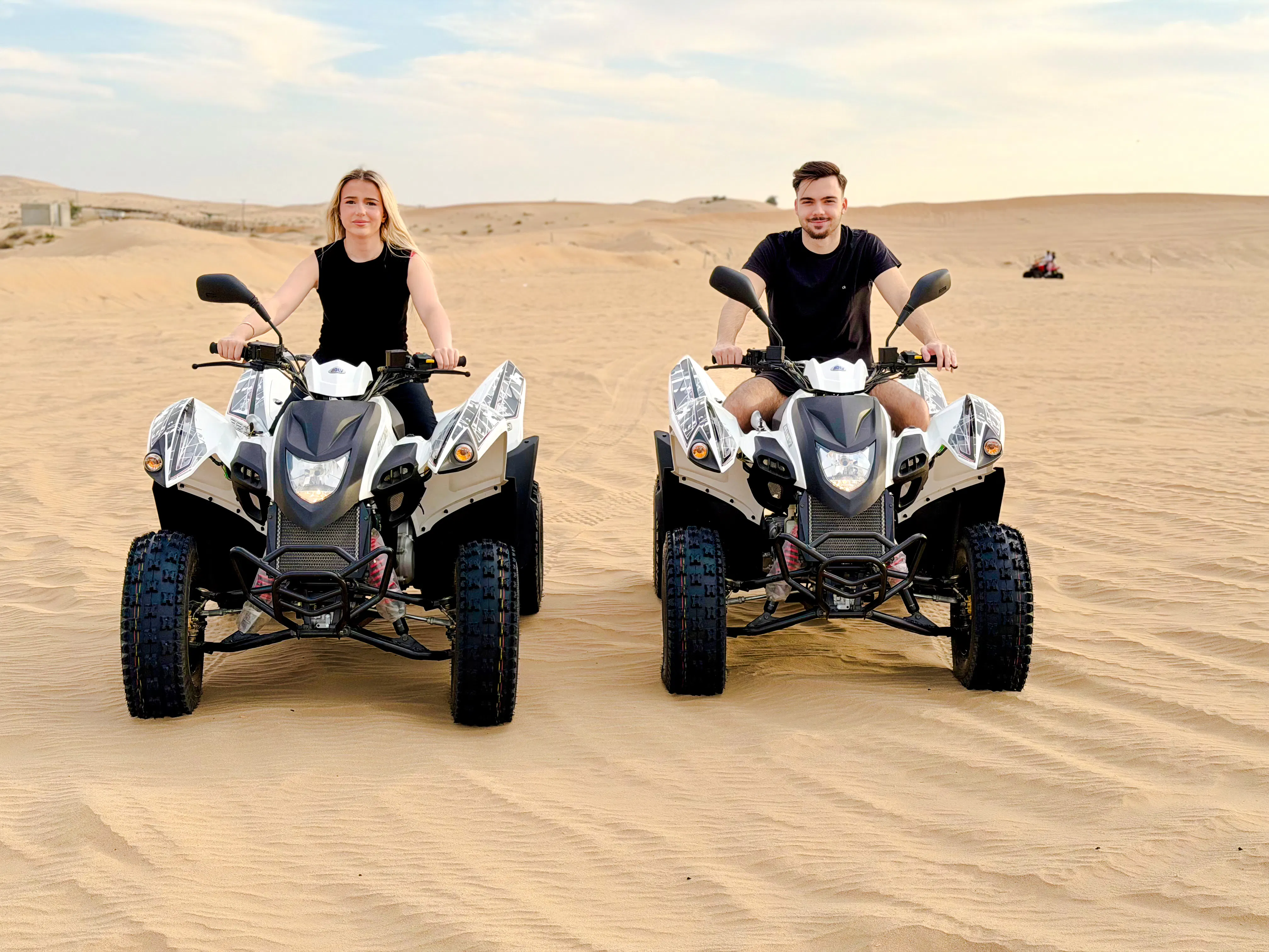 Two people riding quad bikes on a desert safari in Abu Dhabi.