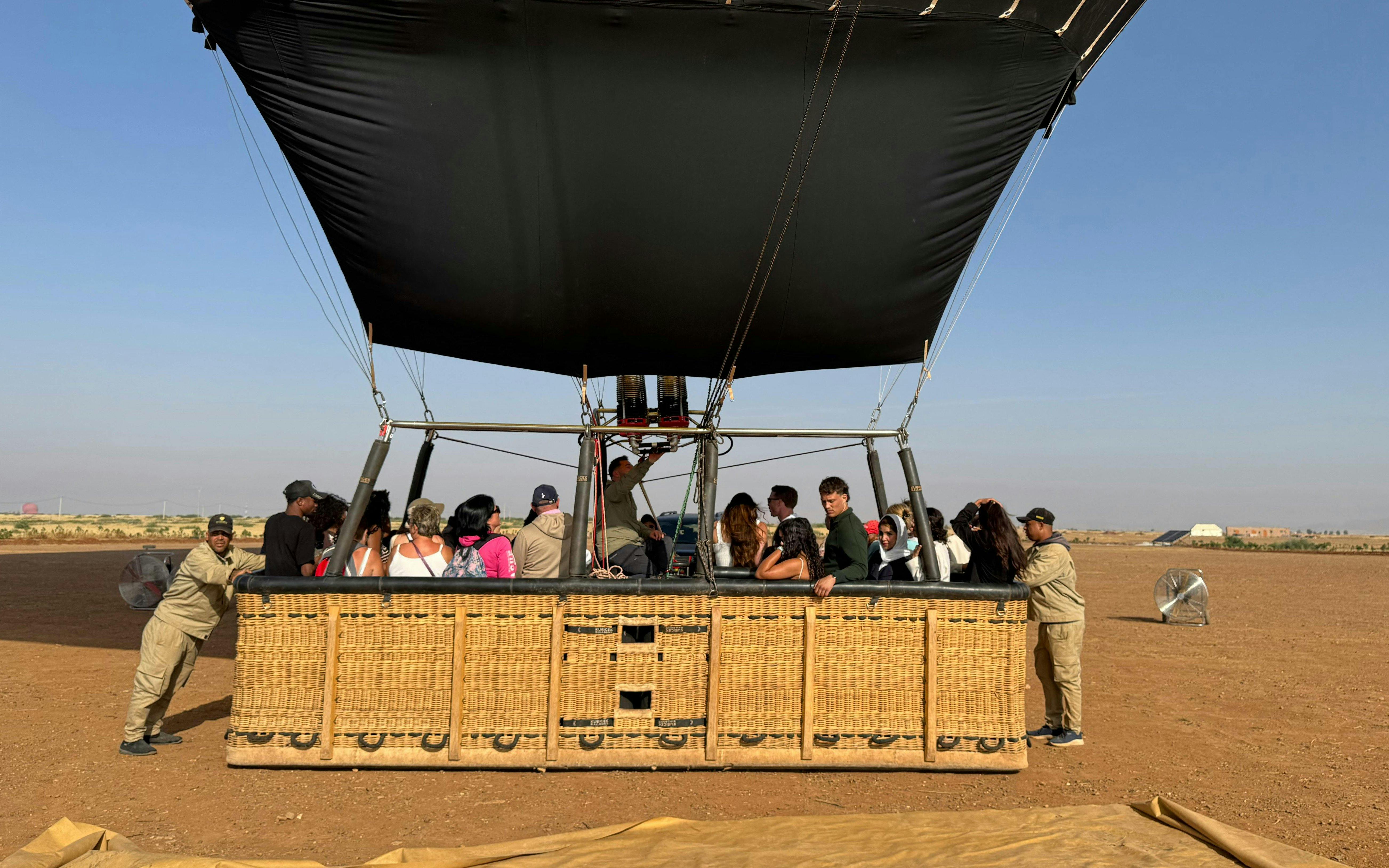 Hot air balloon passengers preparing for flight over Marrakech desert landscape.