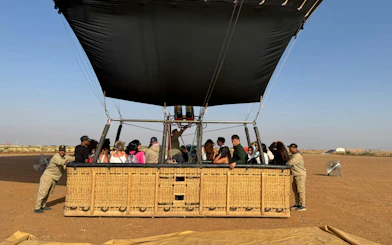 Hot air balloon passengers preparing for flight over Marrakech desert landscape.