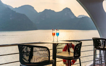 Luxury cruise deck with drinks overlooking Ha Long Bay at sunset.
