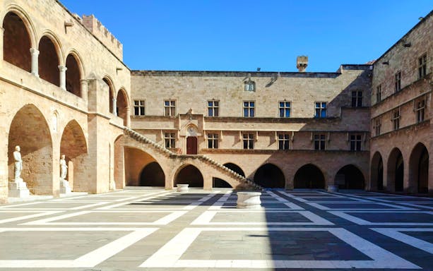 Inner courtyard of the Palace of the Grand Master of the Knights of Rhodes with arches and statues.
