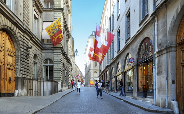 Street in Geneva with Swiss and Geneva flags, part of the Full-Day Guided Tour of Lake Geneva.