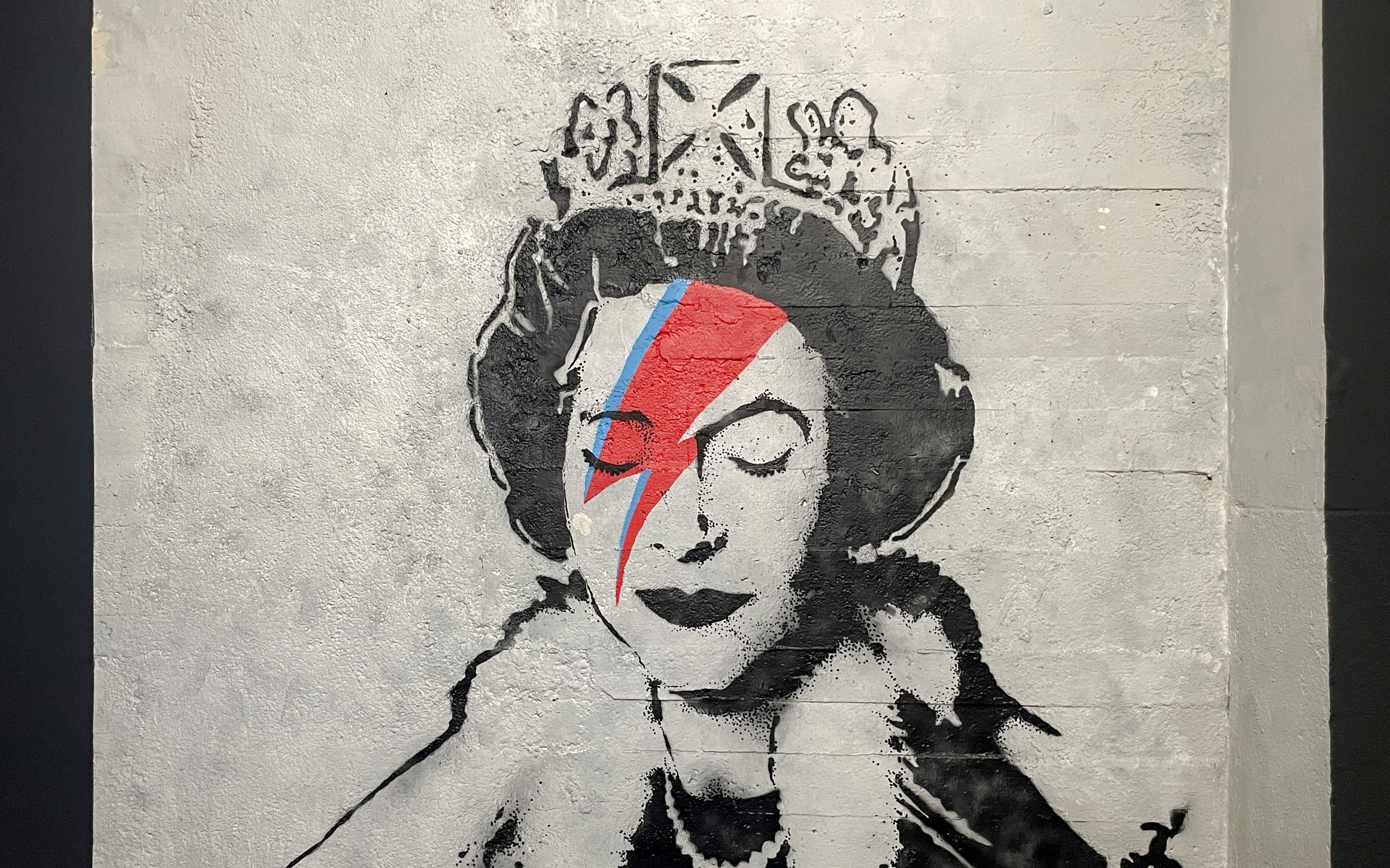 Graffiti of a crowned figure with a red and blue lightning bolt at Banksy Museum Amsterdam.