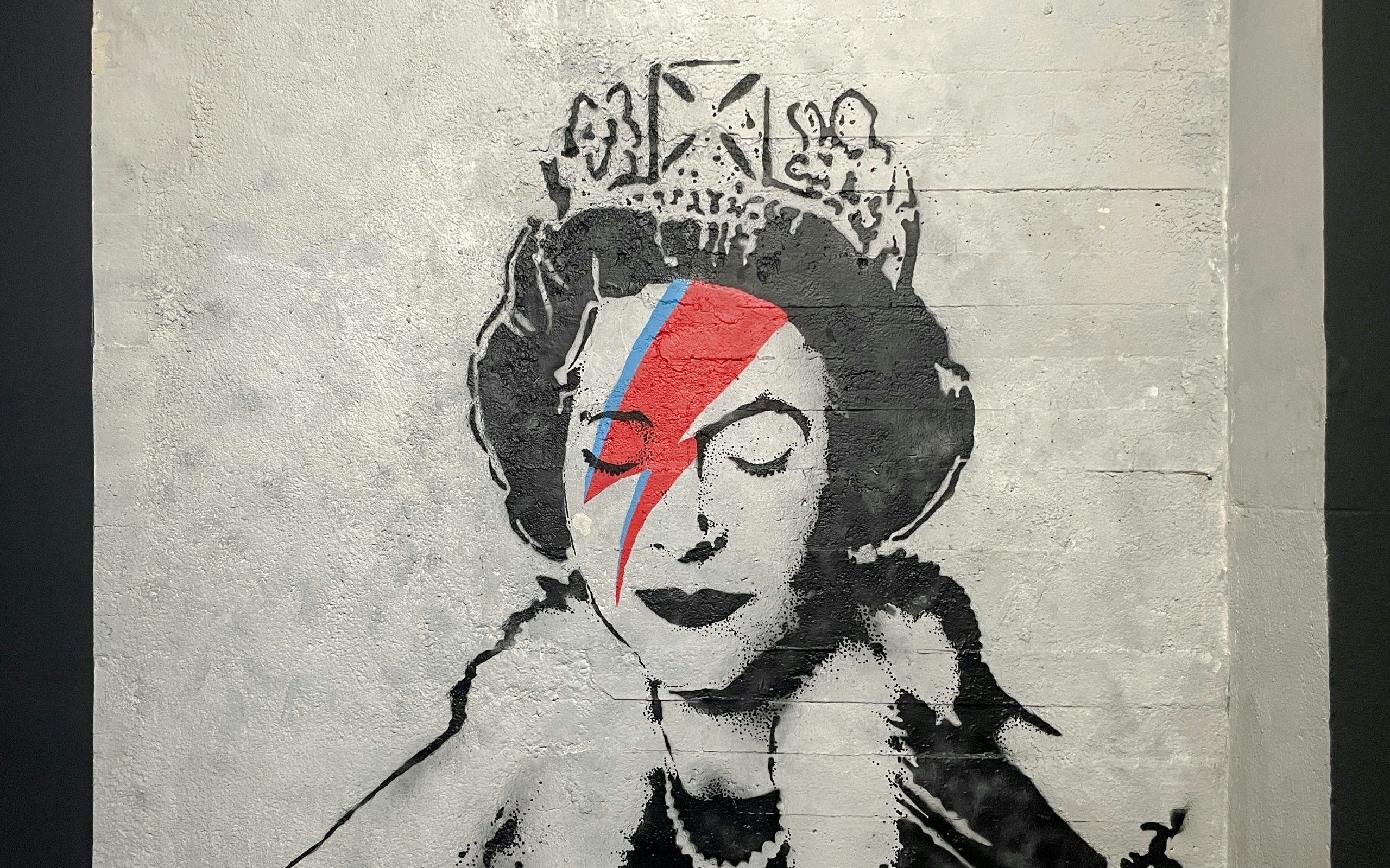 Graffiti of a crowned figure with a red and blue lightning bolt at Banksy Museum Amsterdam.