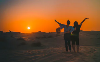 Sunset view during Dubai Desert Safari with two people enjoying the scenery.