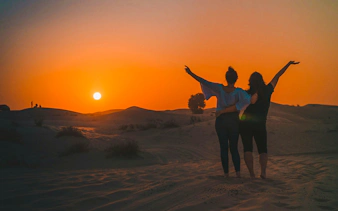 Sunset view during Dubai Desert Safari with two people enjoying the scenery.