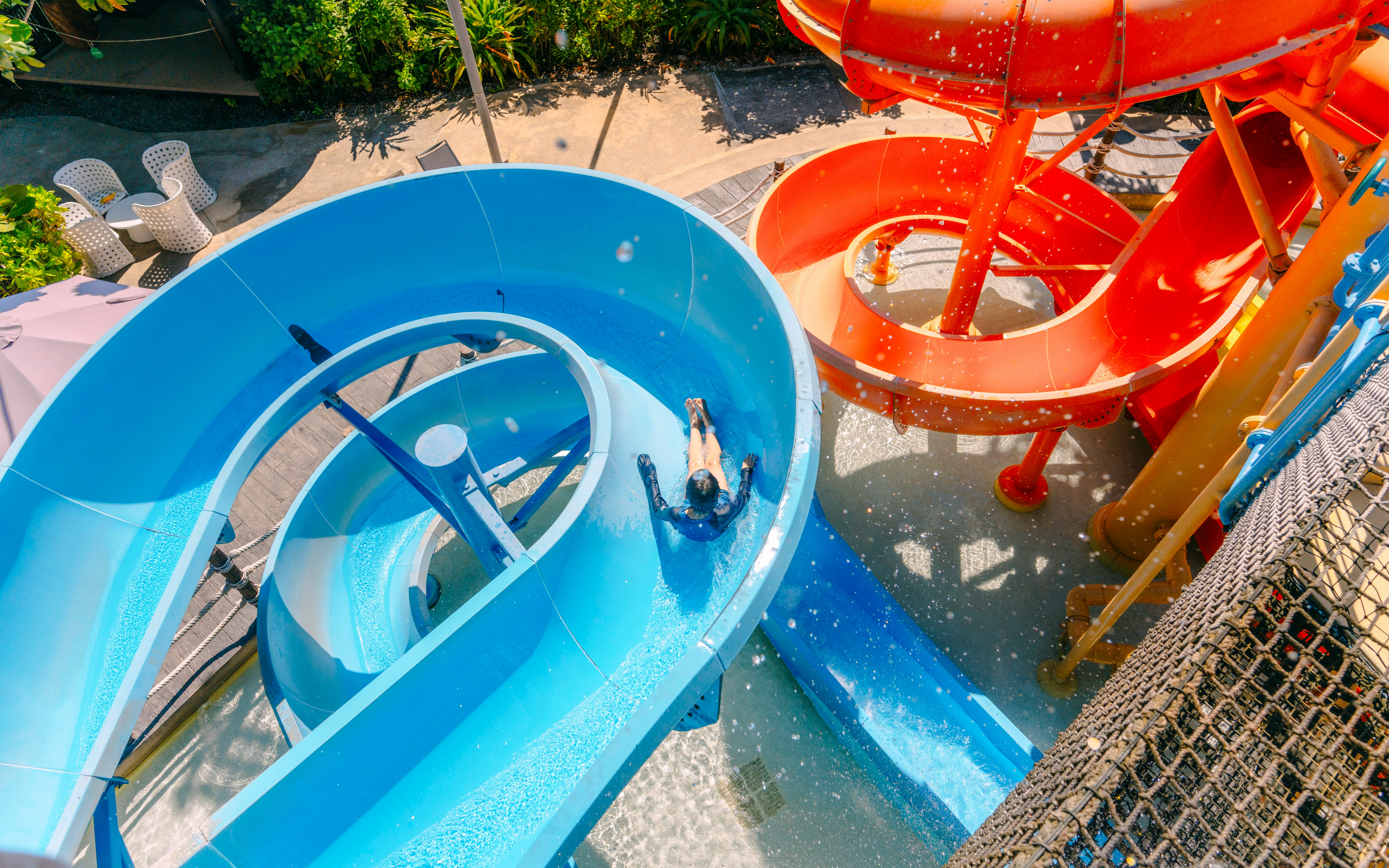 Person sliding down a blue water slide at Vana Nava Water Jungle, Hua Hin.