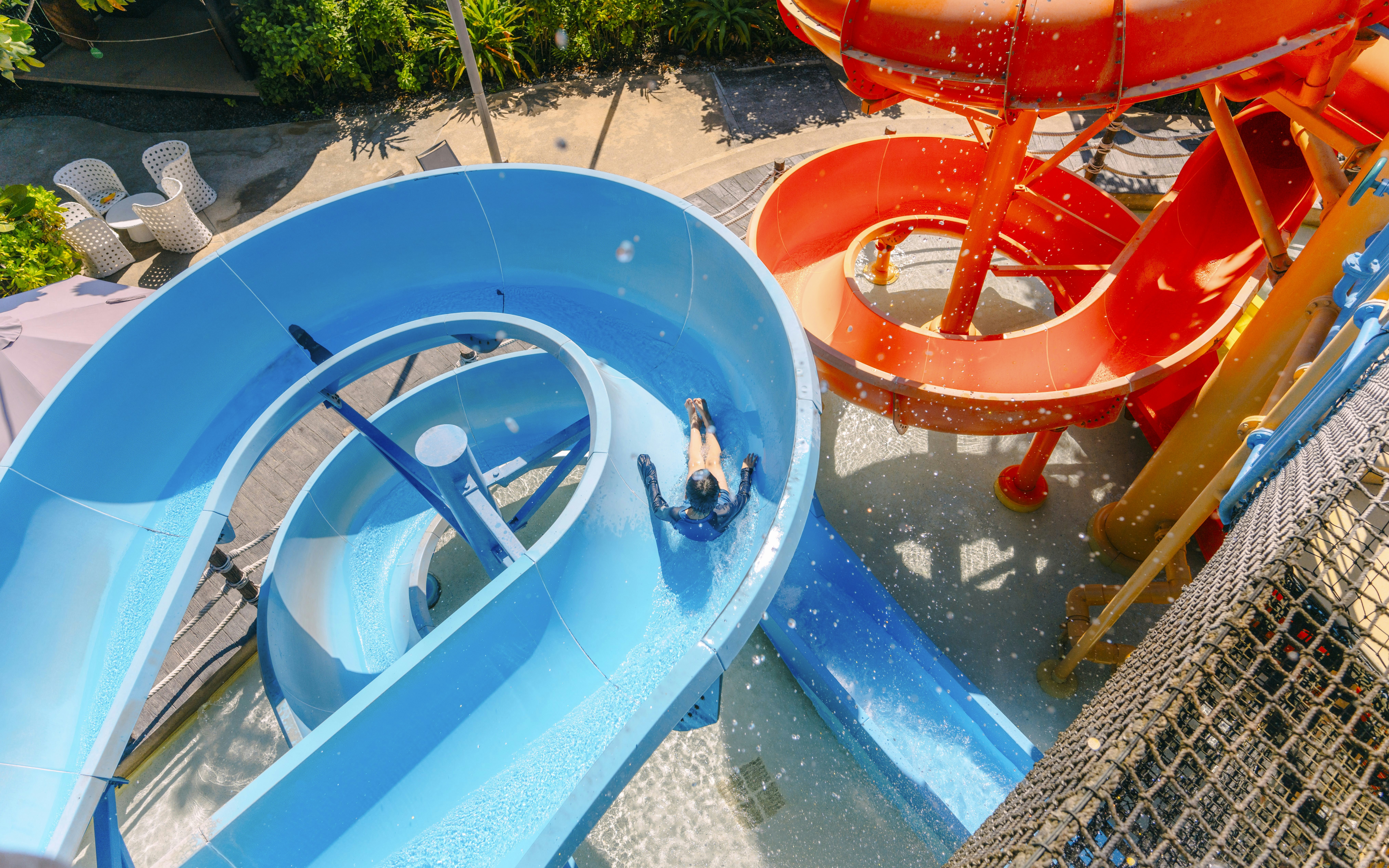 Person sliding down a blue water slide at Vana Nava Water Jungle, Hua Hin.
