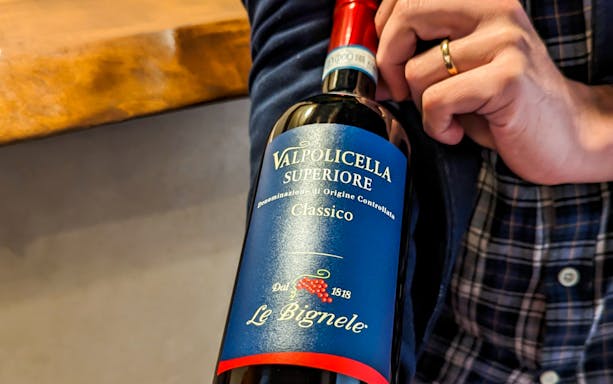 Valpolicella wine bottle held near Juliet's Balcony in Verona.
