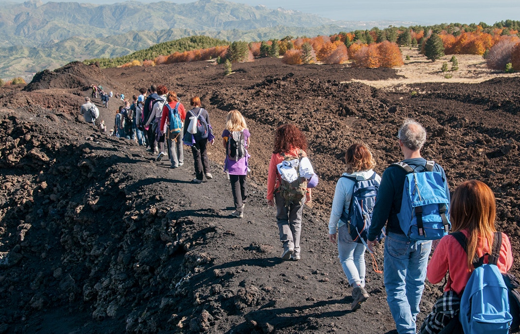 Hikers trekking towards Mount Etna on a guided jeep tour from Taormina, Sicily.