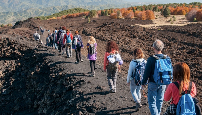 Hikers trekking towards Mount Etna on a guided jeep tour from Taormina, Sicily.