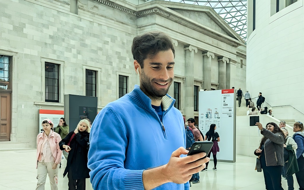 Man using audio guide at British Museum entrance hall.
