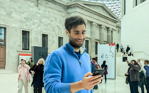 Man using audio guide at British Museum entrance hall.