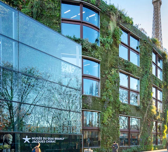 Musée du Quai Branly exterior with vertical garden and Eiffel Tower in Paris.