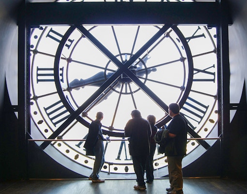 Visitors exploring art at Orsay Museum, Paris, during a guided tour focused on Impressionist masterpieces.