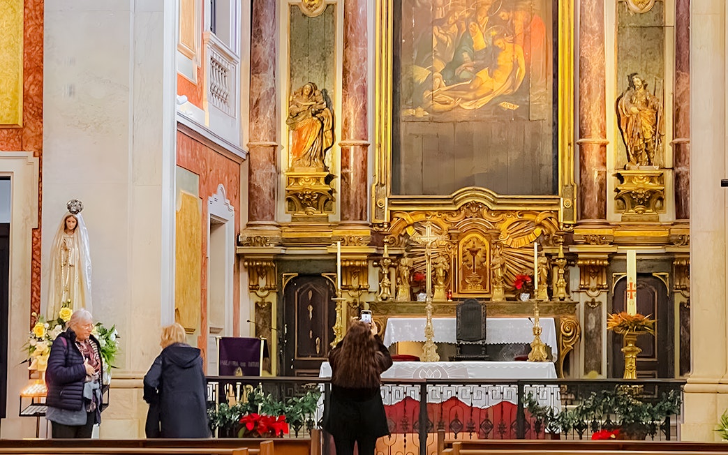 Altar inside St George's Castle Church with visitors and religious statues.