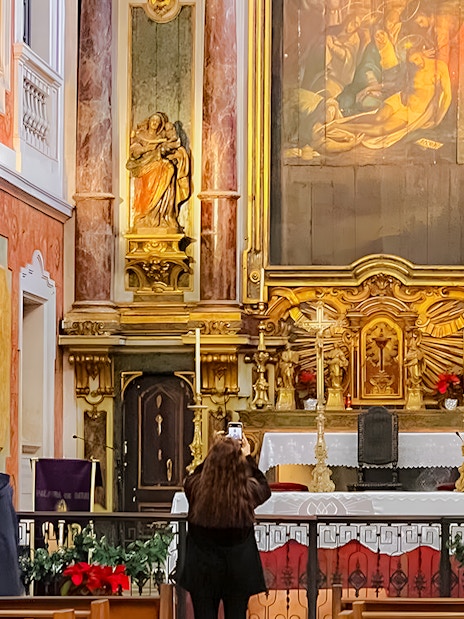 Altar inside St George's Castle Church with visitors and religious statues.