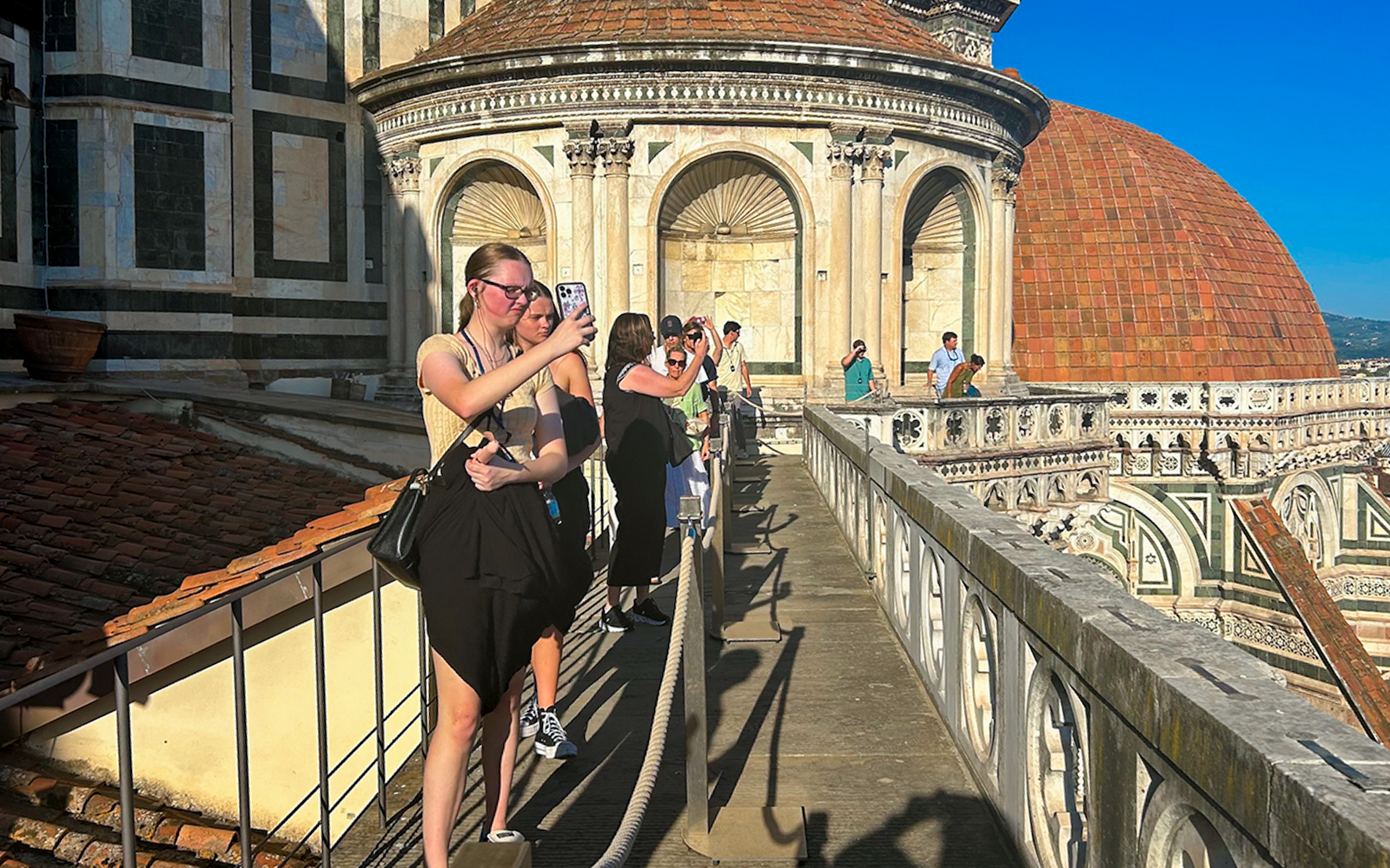 Tourists walking on Florence Duomo terrace, capturing views of the dome.