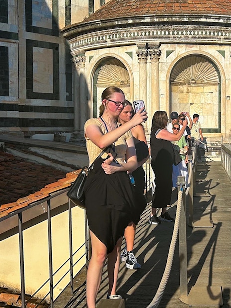 Tourists walking on Florence Duomo terrace, capturing views of the dome.