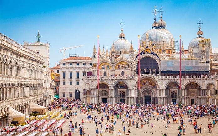 Crowd in front of St. Mark's Basilica, Venice, with ornate domes and arches.