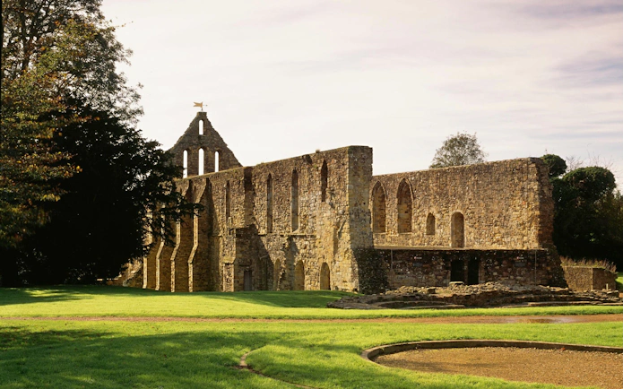 Ruins of Battle Abbey in East Sussex, England, surrounded by green lawns.