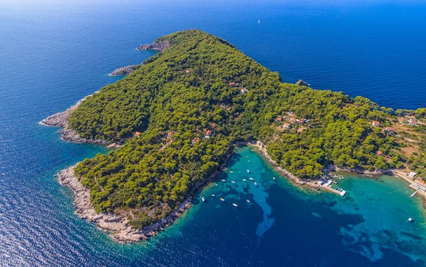 Aerial view of lush green island with boats in turquoise waters, Elaphites, Dubrovnik.