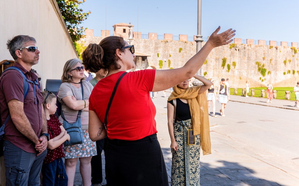 Guide explaining to tourists at the Tower of Pisa Complex.