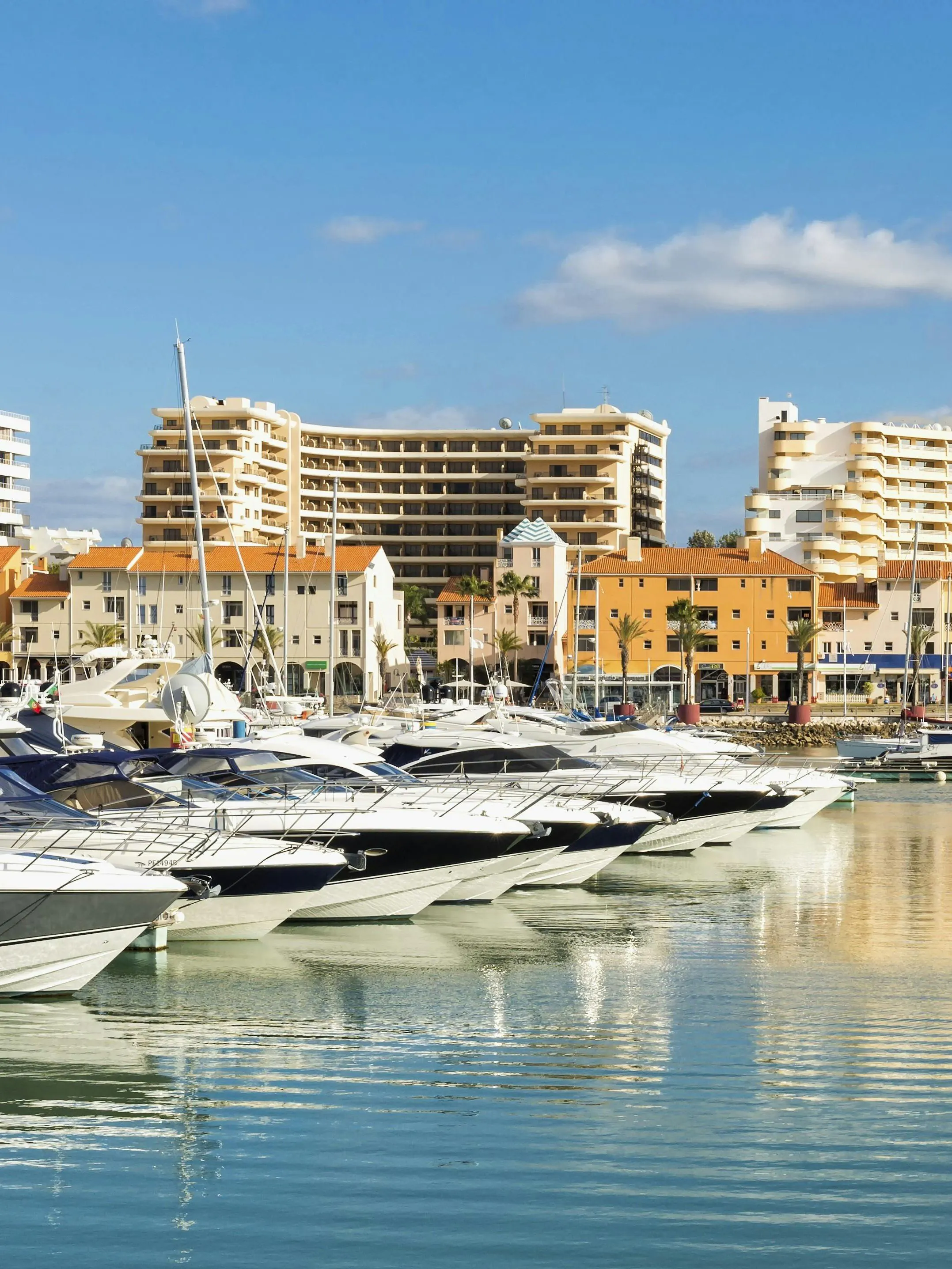 Yachts docked at Marina in Vilamoura, district Faro, Portugal with buildings in the background.