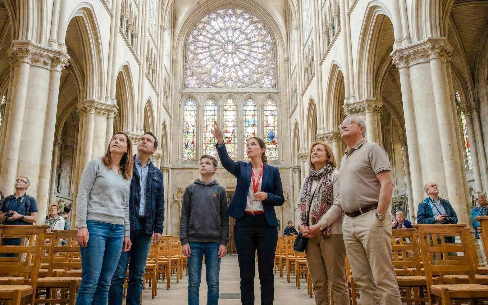Tour group inside Notre-Dame Cathedral, Paris, admiring stained glass windows.